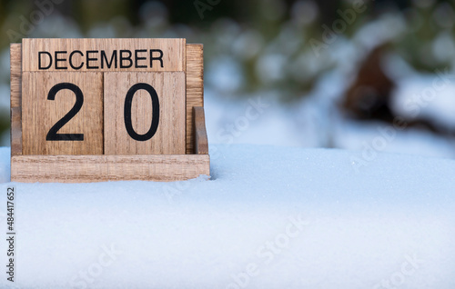 Wooden calendar of December 20 date standing in the snow in nature.