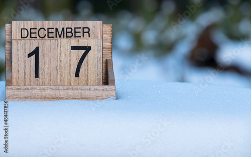 Wooden calendar of December 17 date standing in the snow in nature.