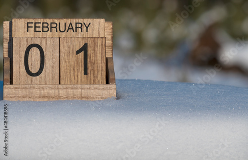 Wooden calendar of February 1 date standing in the snow in nature.