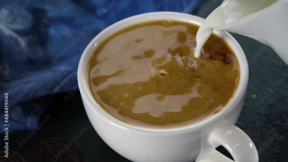 Adding coffee creamer in black coffee. Close- up video of cream or milk pouring in a cup of black coffee Adding coffee creamer in black coffee. Close- up video of cream or milk pouring in a cup of black coffee