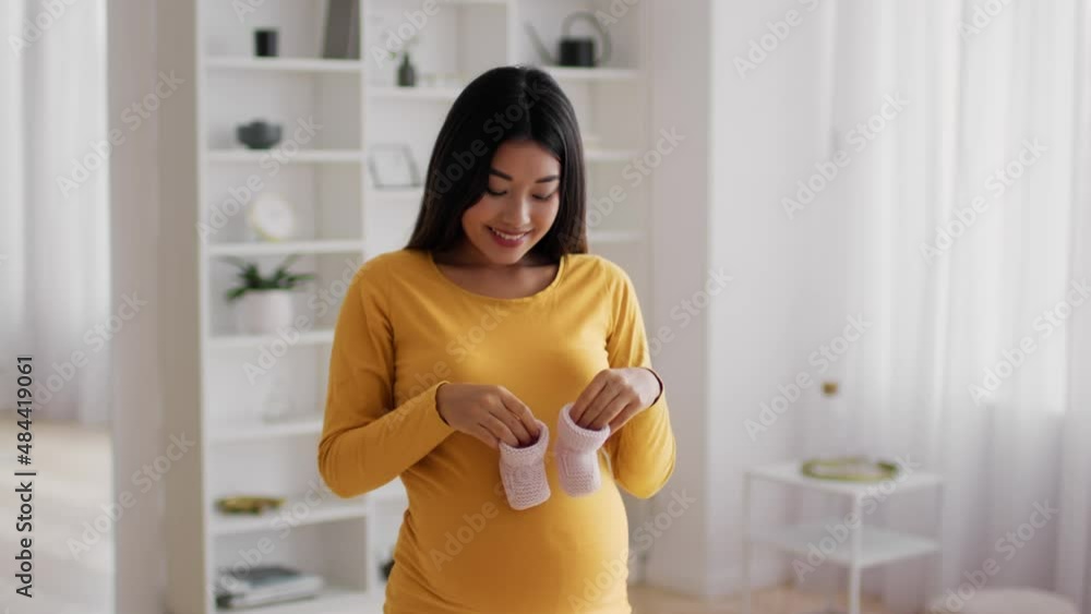 Happy Young Pregnant Asian Woman Playing With Tiny Baby Shoes At Home Happy Young Pregnant Asian Woman Playing With Tiny Baby Shoes At Home