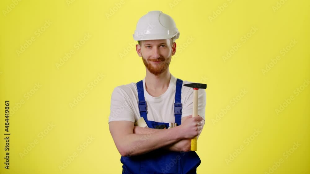 Portrait Of Man Builder Engineer Worker In Hard Hat Helmet With A Hammer Standing And Smile To Camera On The Yellow Background Industrial Site Industry Structure Architecture Inspector Builder Slow Mo Portrait Of Man Builder Engineer Worker In Hard Hat Helmet With A Hammer Standing And Smile To Camera On The Yellow Background Industrial Site Industry Structure Architecture Inspector Builder Slow Mo