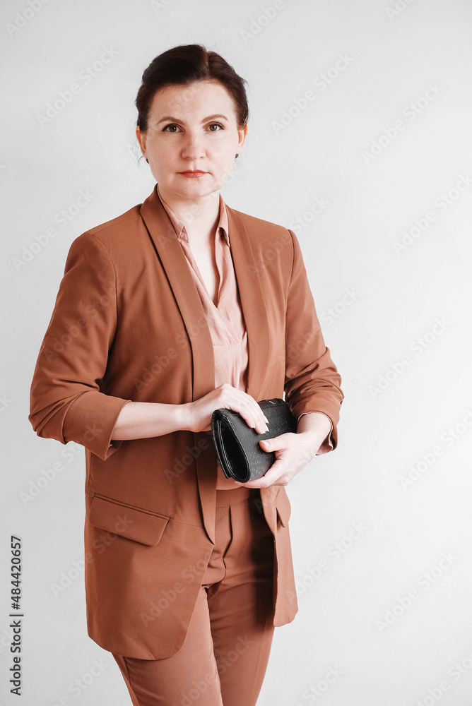 Woman dressed in a brown business suit with a black handbag on a white background. Copy, empty space Woman dressed in a brown business suit with a black handbag on a white background. Copy, empty space