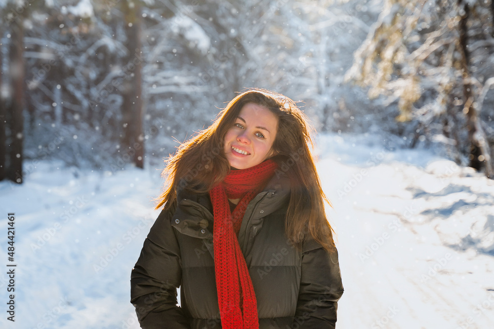 Beautiful young woman in a long down jacket in a snowy forest in winter on a sunny day Beautiful young woman in a long down jacket in a snowy forest in winter on a sunny day