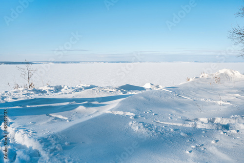 A beautiful frosty landscape with snowdrifts and a frozen river photographed from above. winter desert with blue sky and snow