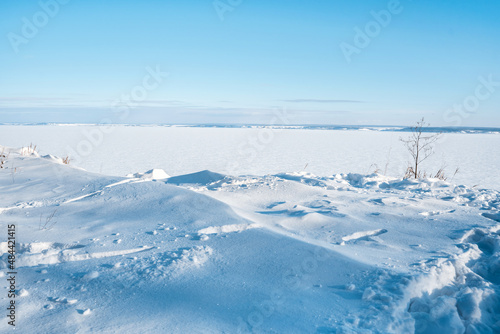 A beautiful frosty landscape with snowdrifts and a frozen river photographed from above. winter desert with blue sky and snow