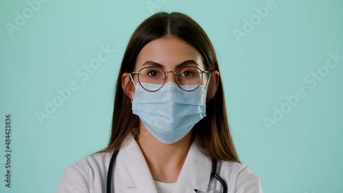 Portrait Of Smiling Caucasian Female Doctor Wear Face Mask Satisfied With Her Job In White Uniform And Stethoscope On A Blue Background Concept Of Medicine, Technology, Health Care And People Hospital