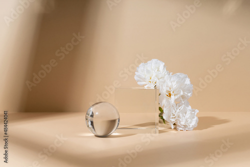 Skincare and cosmetic product showcase stand photography for online marketing include crystal ball and crystal cube stand on beige background with white flower photo