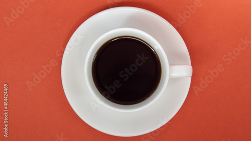 Black coffee in a white coffee cup on a bright background. Top view, flat lay, copy space. Cafe and bar, barista art concept. Freshly made natural or instant coffee in a cup. Coffee background.
