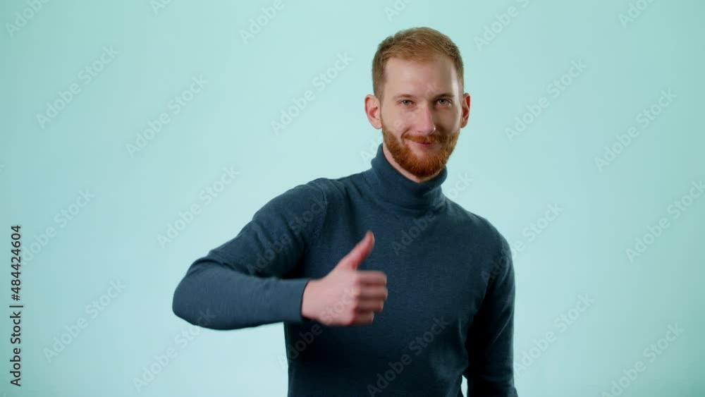 Young Caucasian Positive Man Showing Thumbs Up And Smiles To Camera, Demonstrating Approval, Showing Ok, Gesture Over Blue Color Background Studio. Concept Of People Emotions Lifestyle Young Caucasian Positive Man Showing Thumbs Up And Smiles To Camera, Demonstrating Approval, Showing Ok, Gesture Over Blue Color Background Studio. Concept Of People Emotions Lifestyle