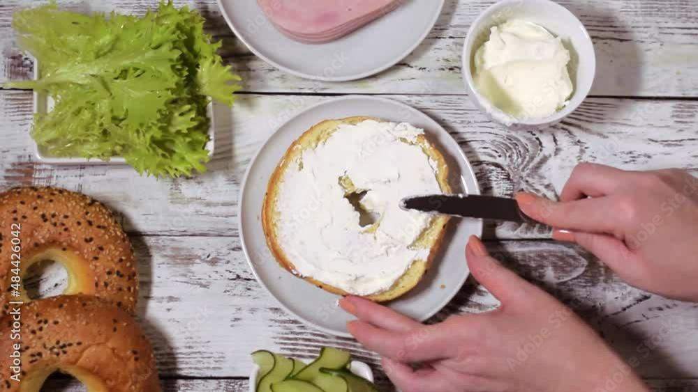 Wideo Stock Spreading cream cheese on the bagel before adding ham