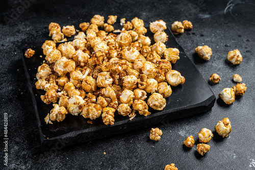 Homemade Crunchy Caramel Popcorn on marble board. Black background. Top view