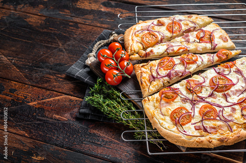 Traditional German pie Flammkuchen or tarte flambee with cream cheese, bacon, tomato and onions. Wooden background. Top view. Copy space photo
