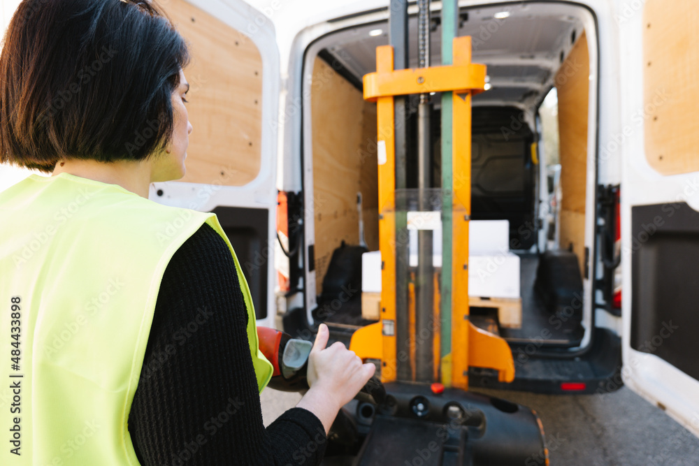 Anonymous woman loading boxes with stacker Anonymous woman loading boxes with stacker