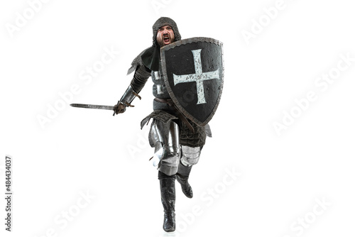 Portrait of brutal seriuos man, medieval warrior or knight with dirty wounded face running with big sword isolated over white background.