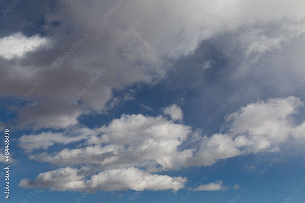 Darkening clouds against a blue sky, creative weather background for copy text, horizontal aspect