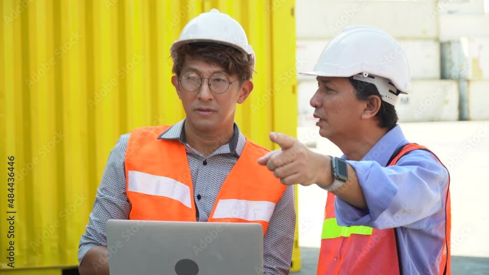 group of two asian engineer holding laptop computer talking with colleague and checking list inventory loading Containers box at warehouse logistic in Cargo . teamwork worker group of two asian engineer holding laptop computer talking with colleague and checking list inventory loading Containers box at warehouse logistic in Cargo . teamwork worker
