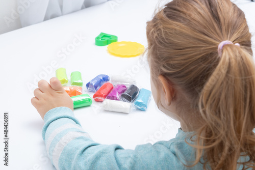 The girl at the table is playing with modeling dough. Childrens games for fine motor skills