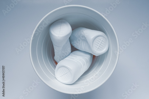White plastic bottles in a trash can on a white background