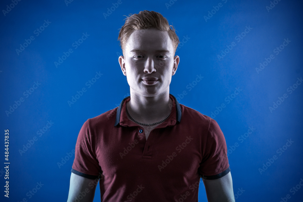 Portrait of a young red-haired athletic confident man in a T-shirt on a blue background. Pumped up. Coach. Sportsman Portrait of a young red-haired athletic confident man in a T-shirt on a blue background. Pumped up. Coach. Sportsman