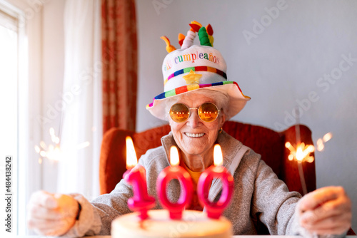 Smiling elderly woman with sparklers celebrating hundredth birthday photo