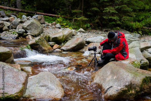 Man is taking photo in mountains river stream. Rainy day in Tatra Mountains, Poland, Europe.