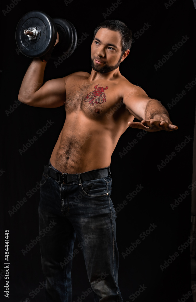 muscular man. athlete trains with heavy dumbbell. studio portrait