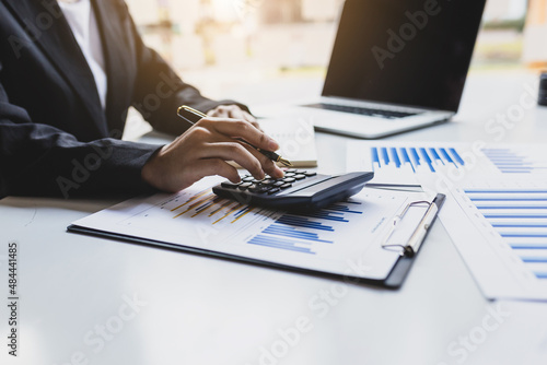 Businesswoman working on her desk using a calculator to calculate income and expenses to manage a budget. Businessman analyzing investment charts with laptop and calculator.