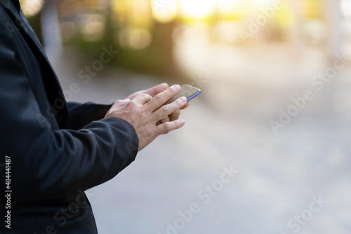 Businessman holding a smartphone using a mobile phone with blurred background.