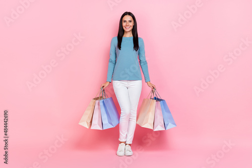 Photo of shiny pretty woman wear blue shirt holding shoppers walking isolated pink color background