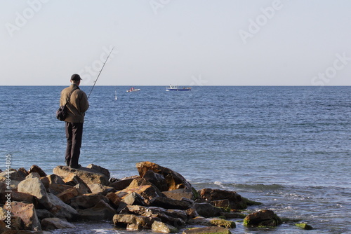 fishing a fisherman stands on the rocks with a spinning rod on the seashore