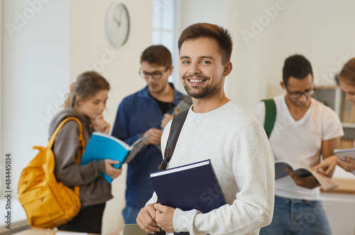 Portrait of smiling millennial Caucasian guy student with backpack pose in public or private college or university. Happy young male learner with textbooks with groupmates in school. Education.
