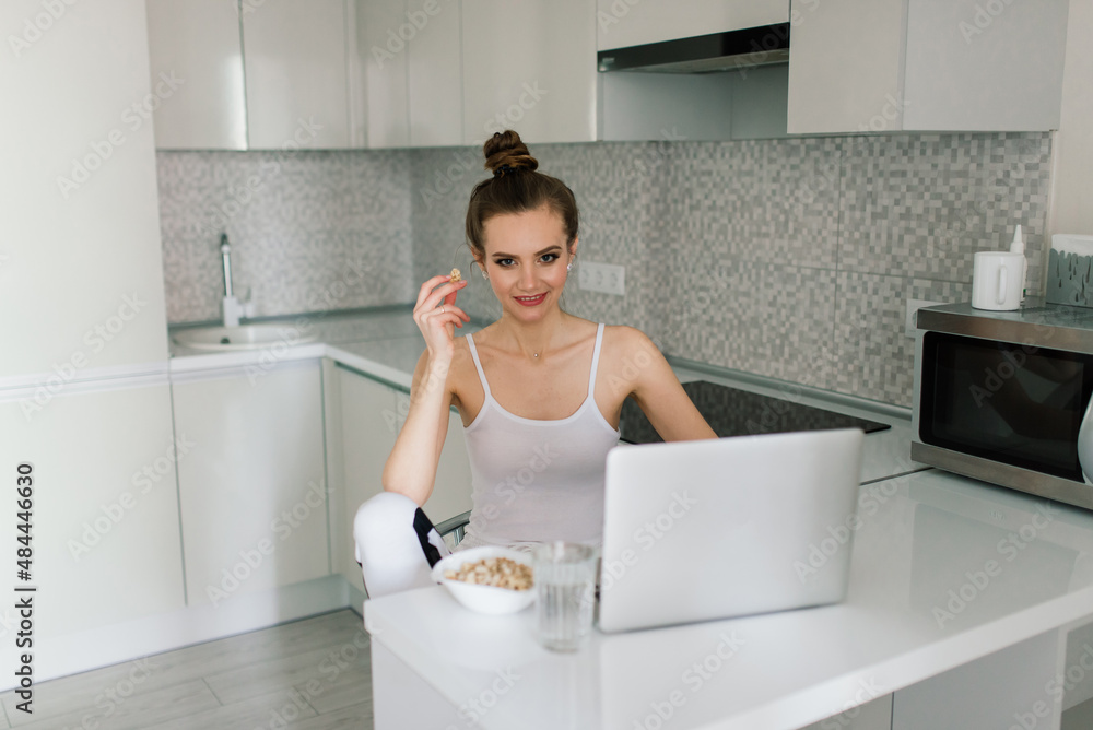 Woman in black suit smiling at the laptop in kitchen Woman in black suit smiling at the laptop in kitchen