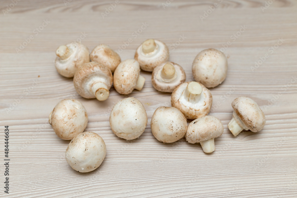Raw fresh champignons on a white wooden table.