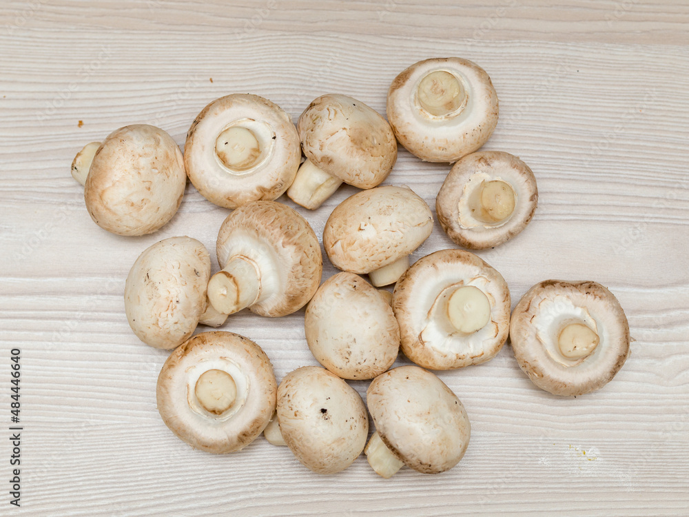 Raw fresh champignons on a white wooden table. Raw fresh champignons on a white wooden table.