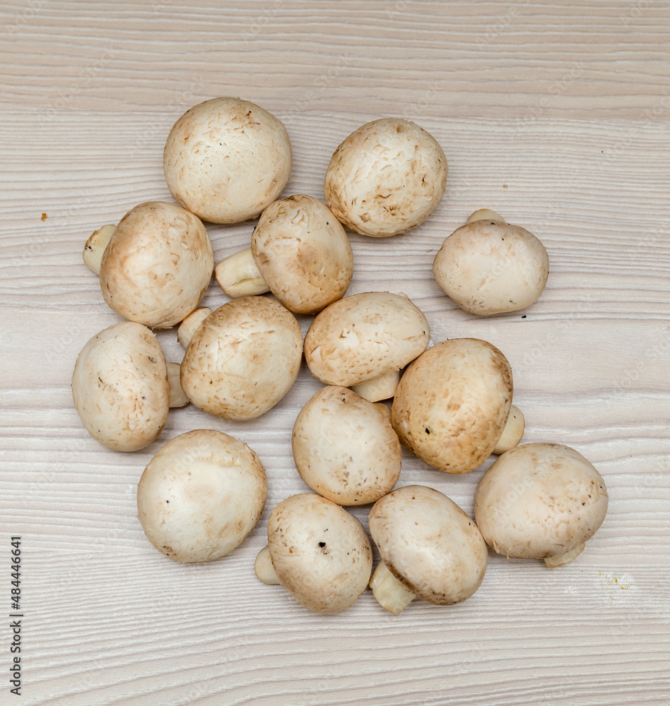 Raw fresh champignons on a white wooden table. Raw fresh champignons on a white wooden table.