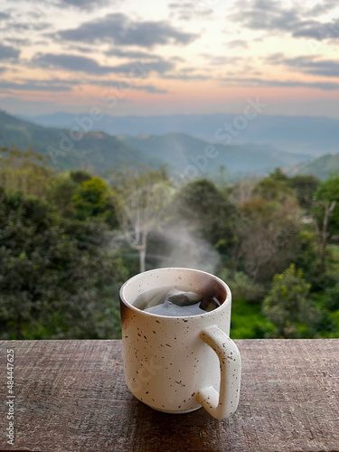 Hot tea cup on the wooden table with beautiful mountain morning sky background concept.