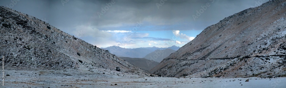 Panorama of snowy mountains and frozen valley at sunrise in the remote Cordillera Huayhuash Circuit near Caraz in Peru.