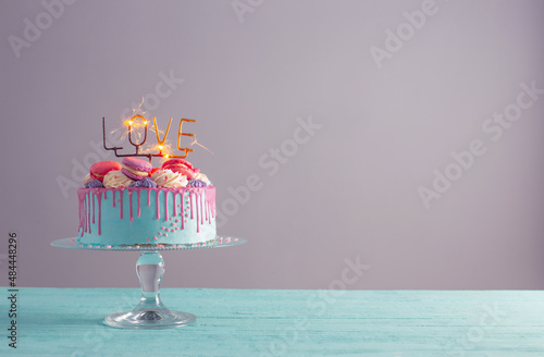 cake with pink and blue decor and burning sparkler with text love