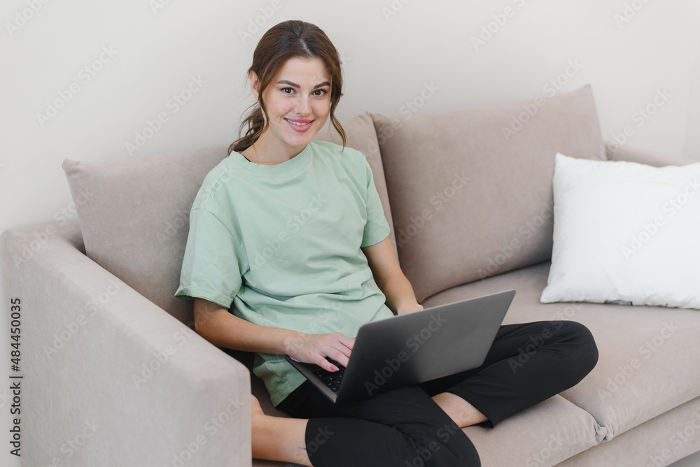 Focused young woman working from home or doing online shopping in living room. Focused young woman working from home or doing online shopping in living room.
