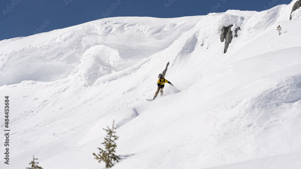 Freerider snowboarder running down the picturesque alpine landscape. Fresh powder snow, blue sky on background. 