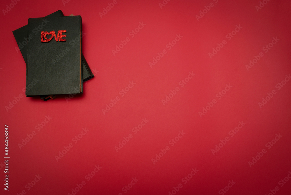 Glossy red letter message LOVE on book on red background. Love valentine concept. Flat lay