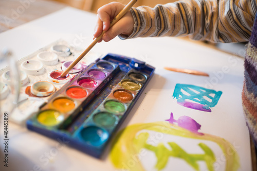 Kinderhand mit Pinsel und Wasserfarbenkasten