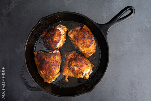 Overhead View of Spice-Rubbed Chicken Thighs in a Cast Iron Skillet: Roasted bone-in skin-on chicken thighs roasted in a cast-iron frying pan