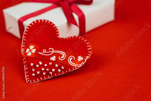 Valentines Day concept with copy space. Red textile heart and goft box on red papper background photo