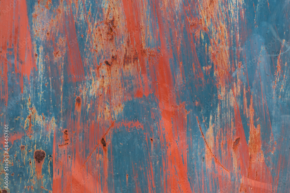 Abstract red and blue paint on rusting metal door. 