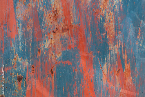 Abstract red and blue paint on rusting metal door. 