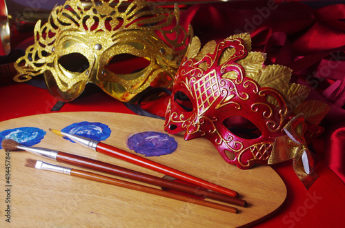 Carnival masks, art palette and brushes on red.
