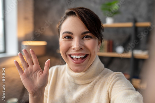 Happy young woman greeting someone via Skype photo