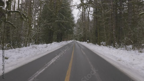 Scenic Road in the Canadian Nature Forest with snow during winter day surrounded by Evergreen Trees. Taken in Squamish, British Columbia, Canada. photo